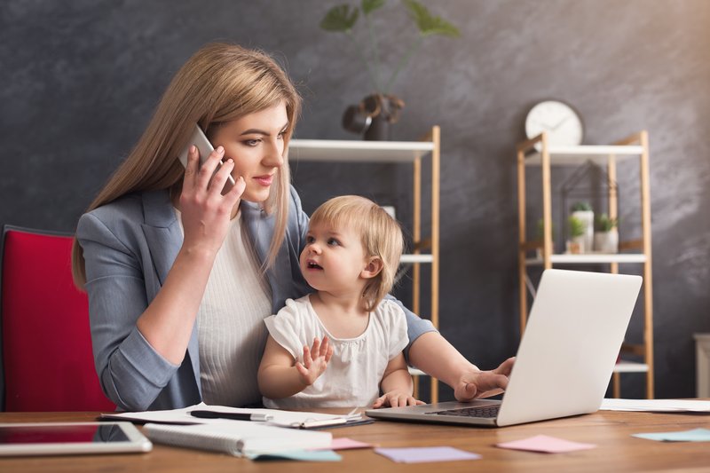 happy-mother-working-office-with-her-baby-young-woman-talking-phone-using-laptop-while-spending-time-with-her-child-business-motherhood-multitasking-family-concept