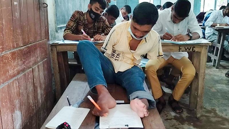 হাত নেই, এক পা দিয়ে লিখে এসএসসি পরীক্ষা দিচ্ছে মানিক