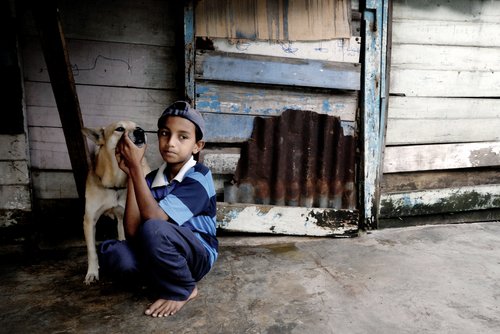 youngster-cradling-dog-outside-aged-wooden-buildin-2026-03-18-11-11-52-utc